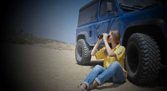 Women next to jeep looking through binoculars